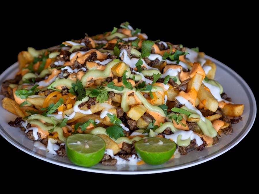 Carne asada fries loaded with cheese, guacamole and chipotle sauce