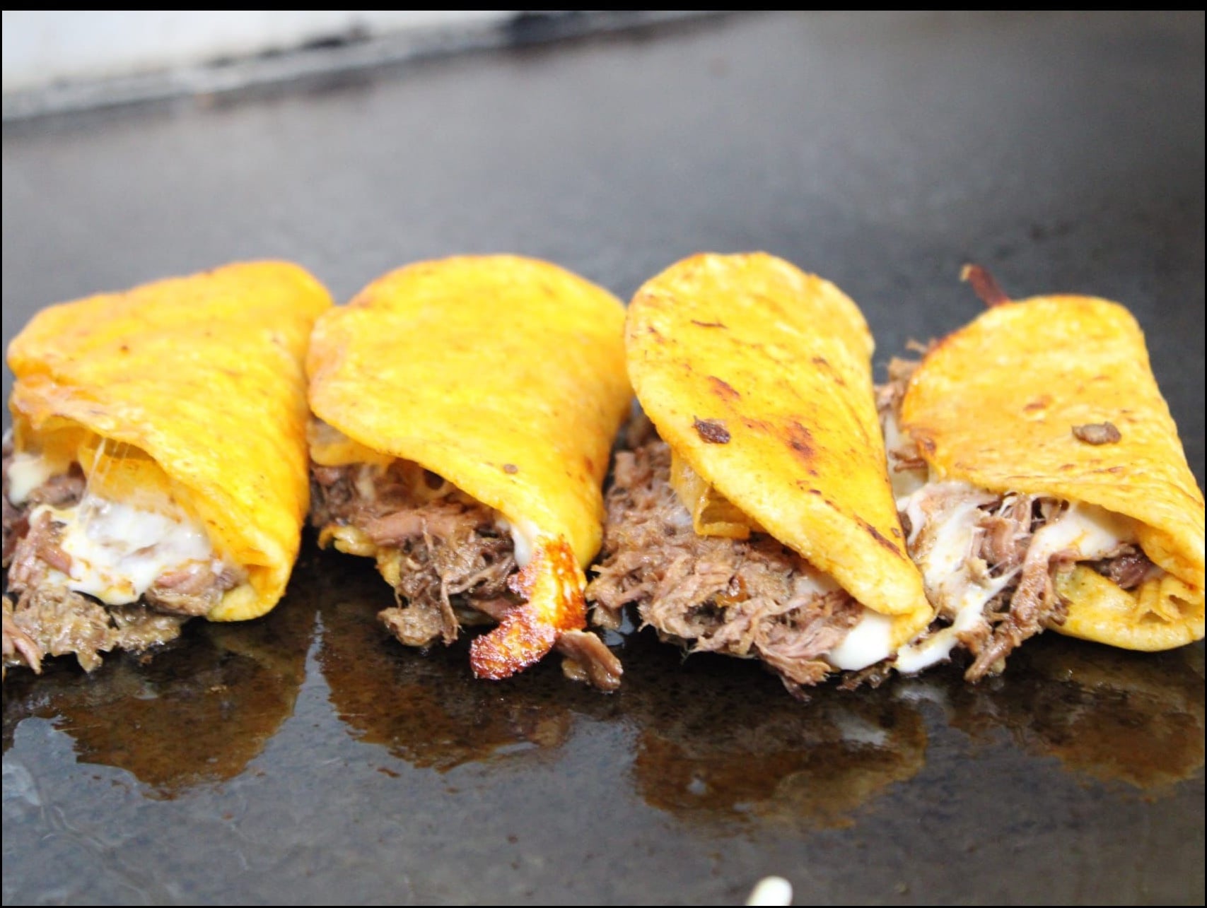 Quesabirria tacos with shredded beef and lime wedges